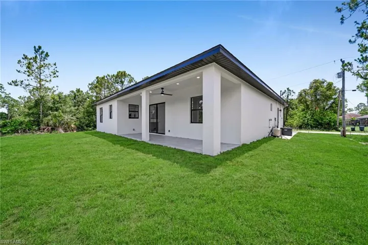 Rear view of house with stucco siding, ceiling fan, a patio area, and a yard