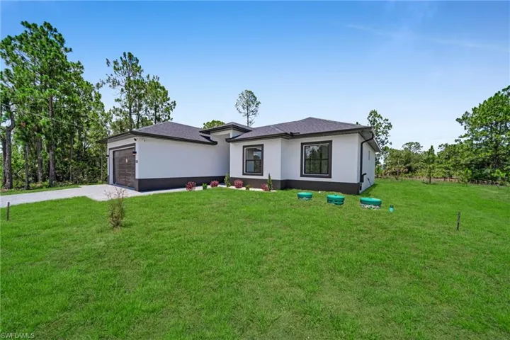 View of front facade with stucco siding, driveway, a front lawn, and an attached garage