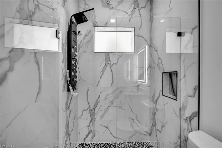 Full bath with a marble finish shower