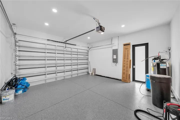 Garage with electric panel, a garage door opener, and recessed lighting
