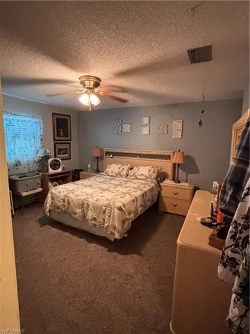 Bedroom featuring dark colored carpet, a ceiling fan, and a textured ceiling