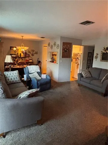 Carpeted living area featuring a chandelier