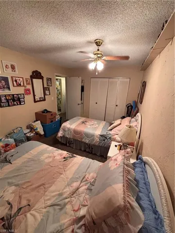 Bedroom featuring a closet, a textured wall, a ceiling fan, and a textured ceiling
