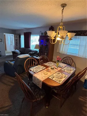 Carpeted dining space with a chandelier and a textured ceiling