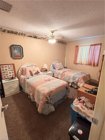 Bedroom featuring carpet, a textured ceiling, and a ceiling fan