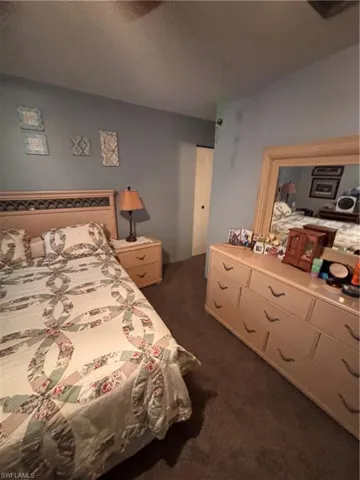 Bedroom featuring dark colored carpet and a textured ceiling