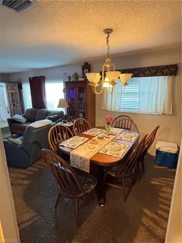 Carpeted dining space with a chandelier and a textured ceiling