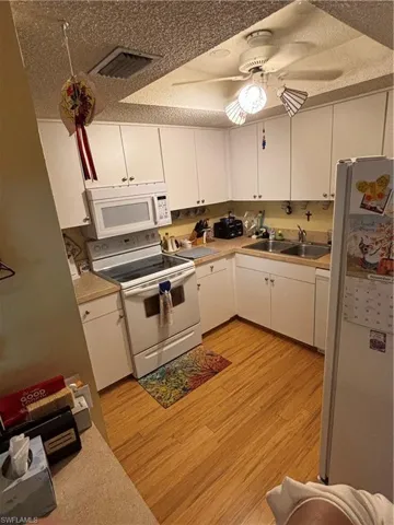 Kitchen with white cabinetry, white range, light countertops, and a textured ceiling