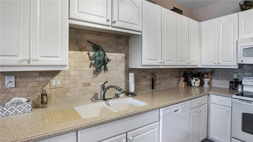 Kitchen with white appliances, white cabinets, and decorative backsplash