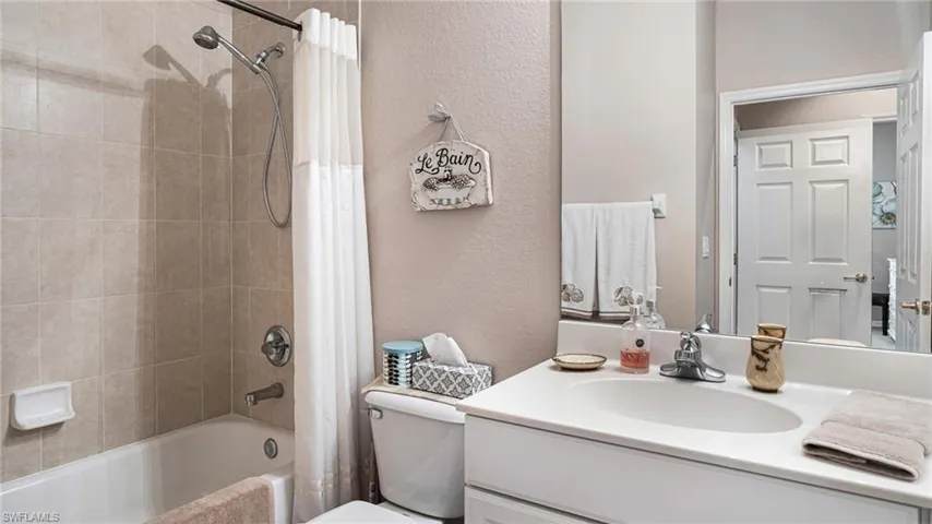 Guest bathroom with toilet, shower / tub combo with curtain, and vanity