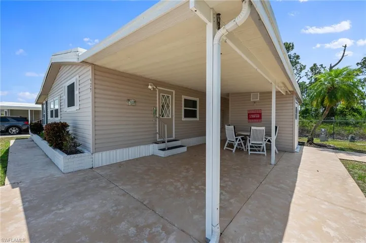 View of patio / terrace with concrete driveway, a carport, entry steps, and fence