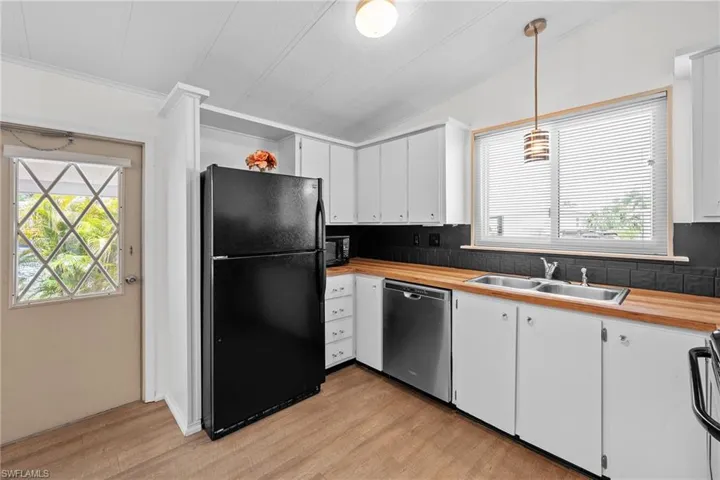 Kitchen featuring butcher block counters, tasteful backsplash, a sink, and black appliances