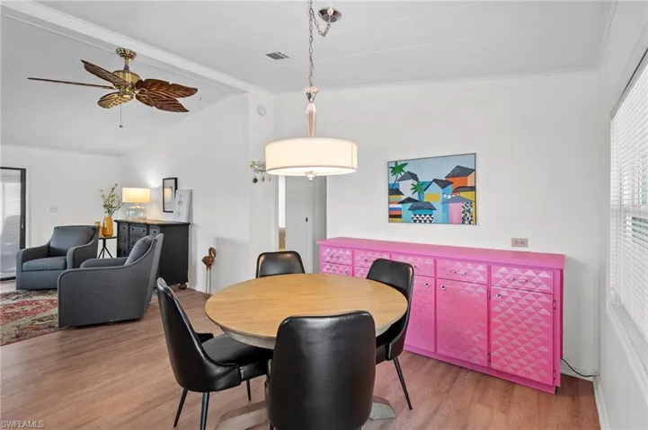 Dining space with a ceiling fan, wood finished floors, vaulted ceiling with beams, and visible vents