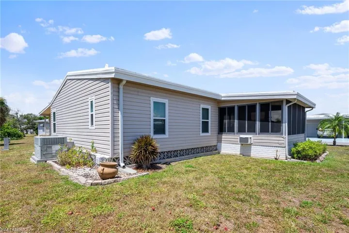Back of house with central AC unit, a sunroom, and a lawn
