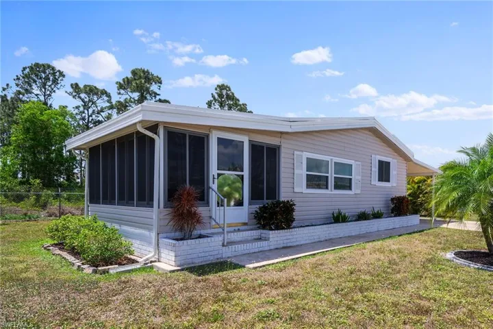 View of property exterior featuring a yard, fence, and a sunroom