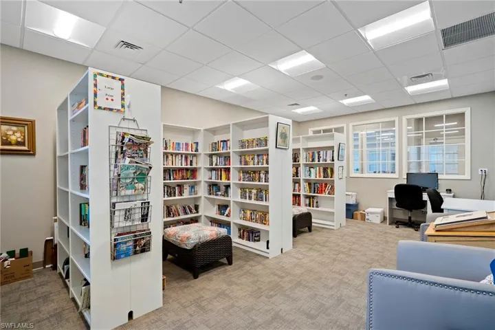 Carpeted home office with visible vents, a paneled ceiling, and wall of books