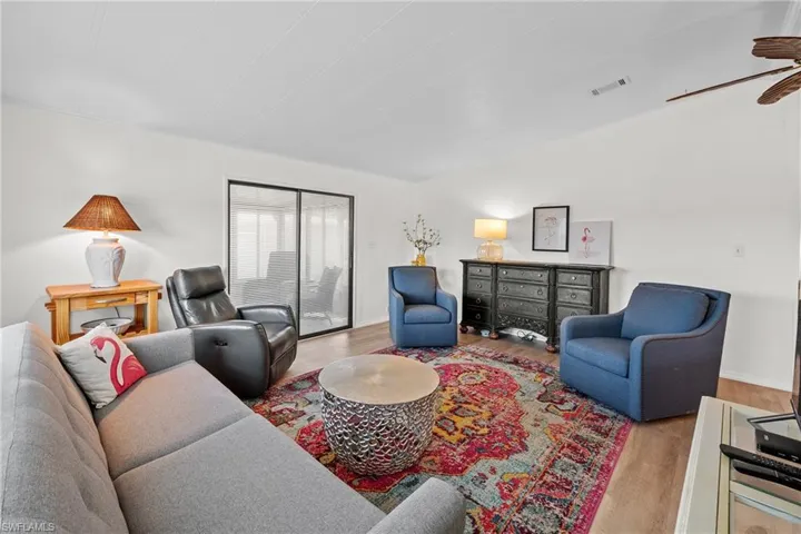 Living room with visible vents, ceiling fan, and wood finished floors