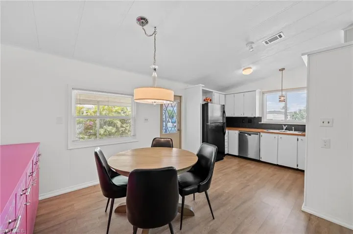 Dining space with visible vents, baseboards, vaulted ceiling, and light wood-style floors