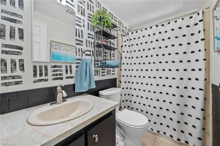 Bathroom featuring toilet, curtained shower, and vanity
