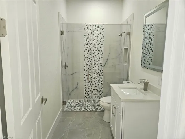 Bathroom featuring vanity, a marble finish shower, and a textured wall