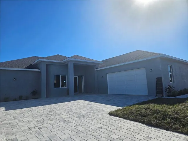 Ranch-style home featuring decorative driveway, stucco siding, an attached garage, and roof with shingles