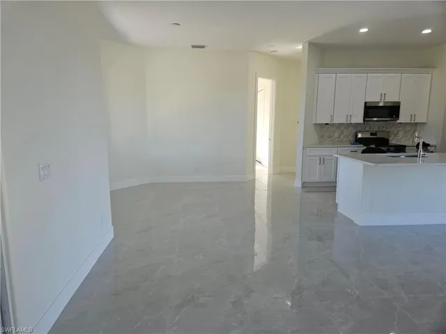 Kitchen with white cabinets, appliances with stainless steel finishes, tasteful backsplash, light marble finish floors, and recessed lighting