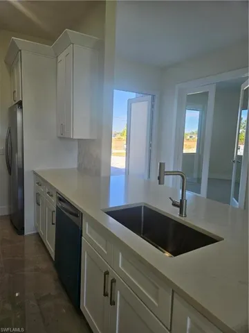Kitchen with white cabinets, refrigerator, dishwashing machine, and decorative backsplash