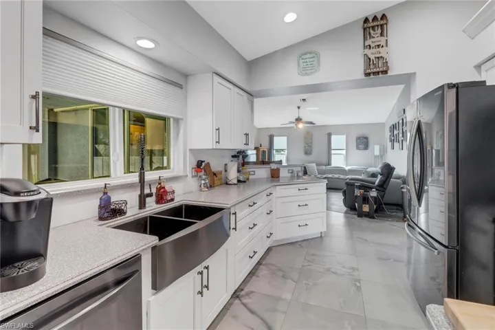 Kitchen with lofted ceiling, white cabinets, ceiling fan, sink, and stainless steel appliances