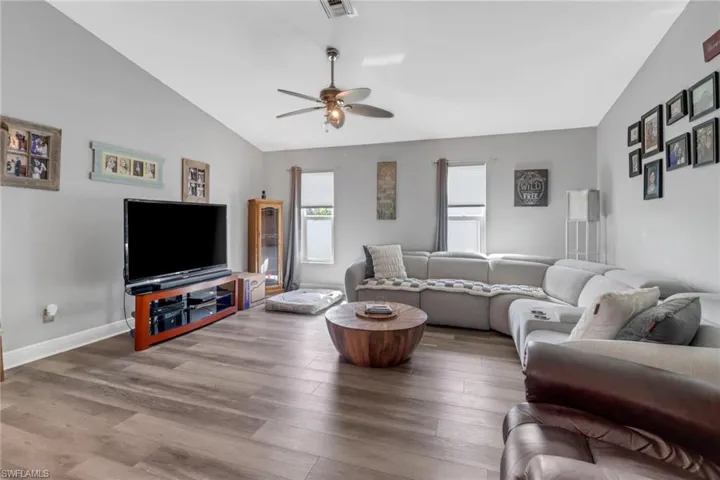 Living room featuring ceiling fan, wood-type flooring, and lofted ceiling