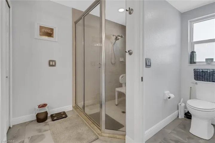 Bathroom featuring toilet and a shower with shower door