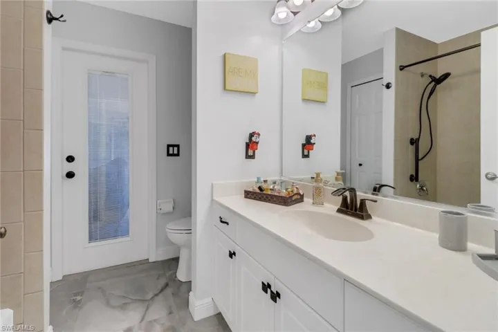 Bathroom featuring vanity, a tile shower, and toilet