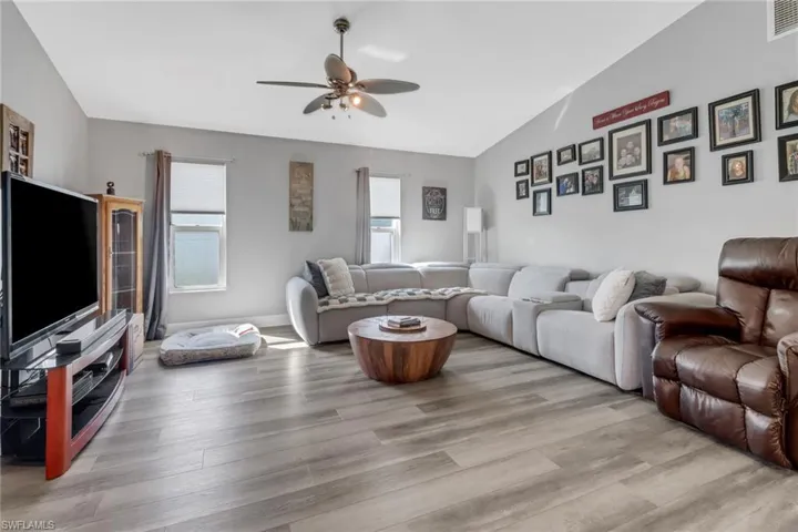Living room featuring ceiling fan, light wood-type flooring, and vaulted ceiling