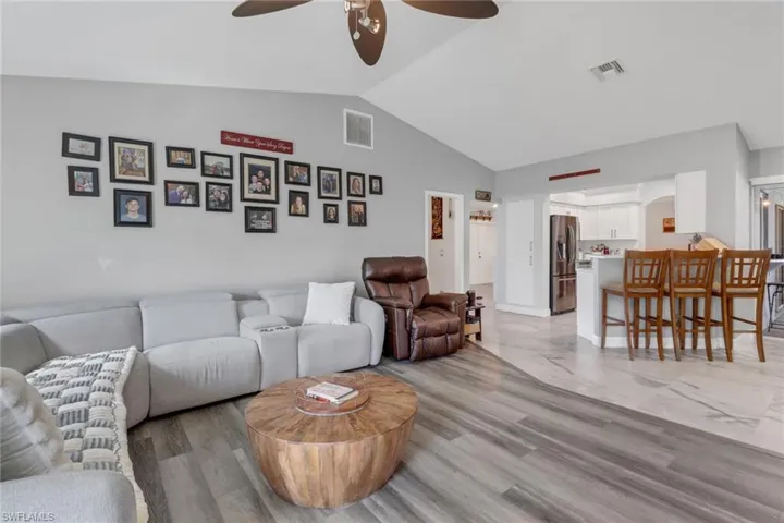Living room with light hardwood / wood-style flooring, ceiling fan, and vaulted ceiling