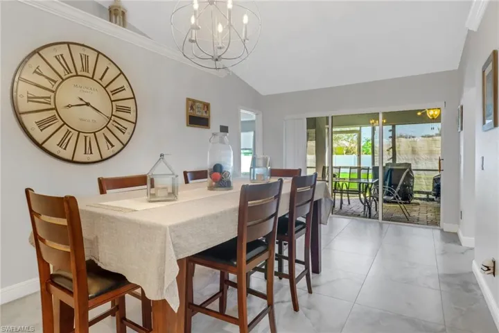 Tiled dining area featuring lofted ceiling, crown molding, and a notable chandelier