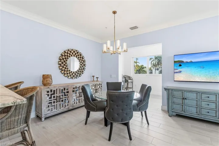Dining area with ornamental molding, wood tiled floors, and hanging lights