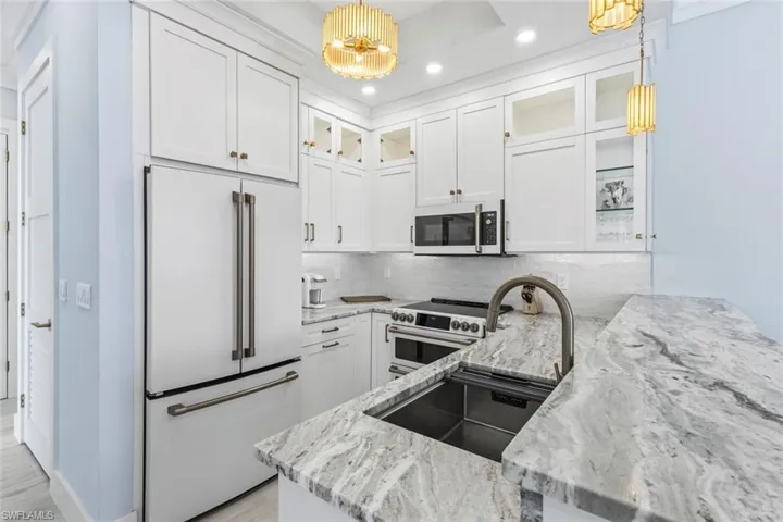 Kitchen featuring white cabinets, glass fronted cabinets, white appliances, and light stone countertops