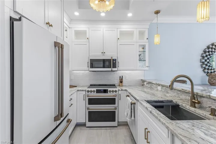 Kitchen with white cabinetry, light stone counters, and high quality appliances