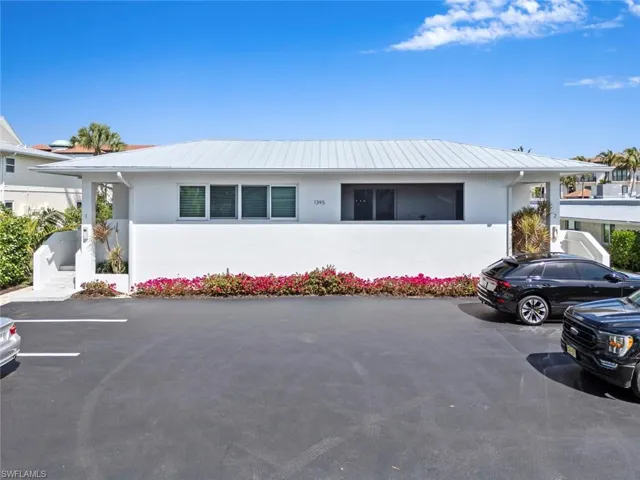 Front view of Condo with 2 assigned parking spots right at front door, stucco siding, and a metal roof