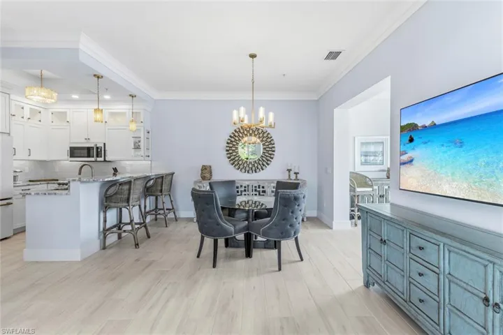 Dining area with a chandelier, light Ceramic Tile flooring, and ornamental molding