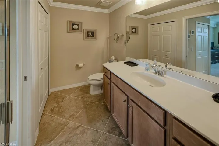 Bathroom with vanity, ornamental molding, and tile patterned floors