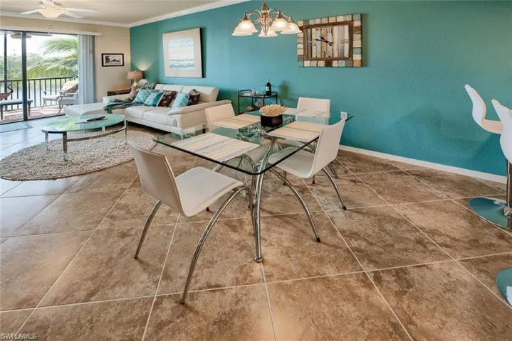 Tiled dining area with crown molding and a chandelier