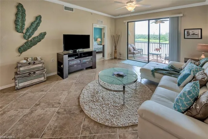 Living room with crown molding, ceiling fan, and tile patterned flooring