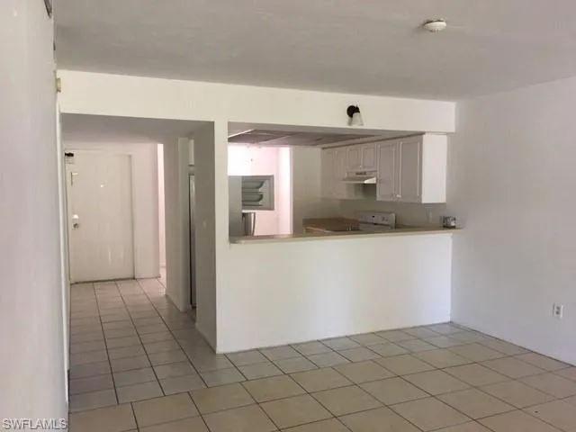 Kitchen featuring range, light tile patterned floors, and white cabinetry
