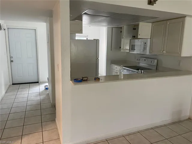 Kitchen featuring white appliances, white cabinets, and light tile patterned flooring