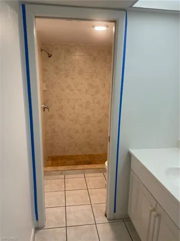 Bathroom featuring tiled shower, vanity, and tile patterned flooring
