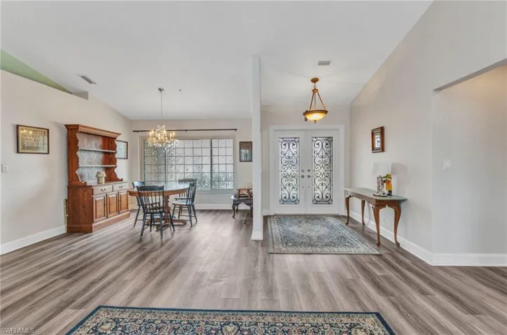 Entryway with french doors, wood finished floors, and vaulted ceiling