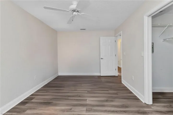 Unfurnished bedroom featuring a spacious closet, visible vents, baseboards, wood finished floors, and a closet