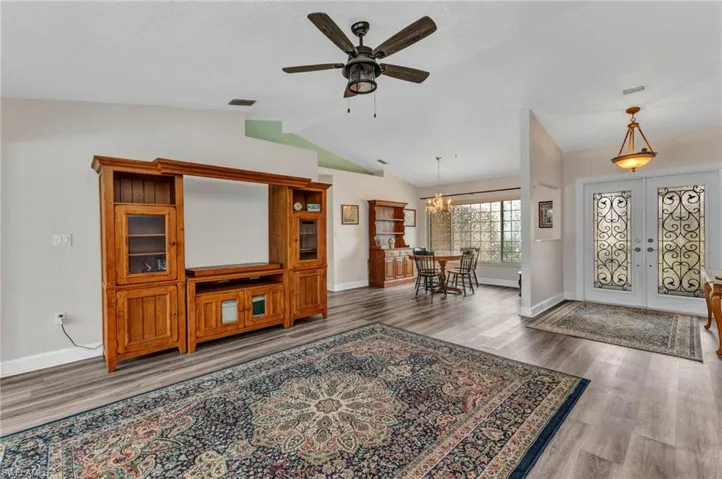 Entryway with visible vents, ceiling fan with notable chandelier, wood finished floors, french doors, and lofted ceiling