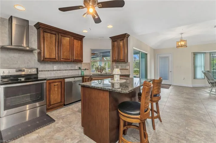 Kitchen with wall chimney exhaust hood, a healthy amount of sunlight, tasteful backsplash, and stainless steel appliances