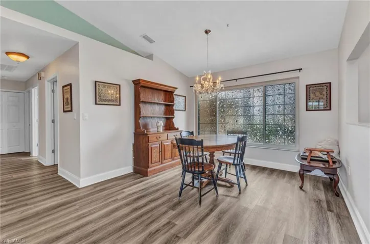 Dining room featuring visible vents, a notable chandelier, lofted ceiling, light wood finished floors, and baseboards
